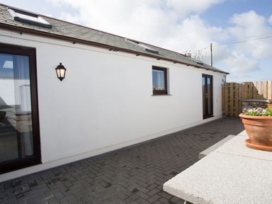 An outdoor patio area with white walls windows and a flowerpot at Cornish Views in Camborne