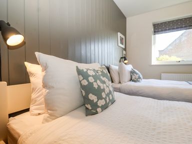 A bedroom with two beds white bedding floral pillows and a window at Mundays in Orford