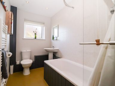 A bathroom with a toilet sink bathtub window and towel rack at Mondays in Orford