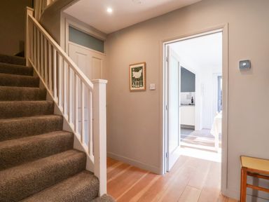 A carpeted staircase beside a hallway leading to a kitchen at Mundays in Orford