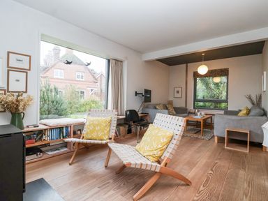 A living room with two wooden lounge chairs with yellow cushions and a window bench with books at Mundays Orford