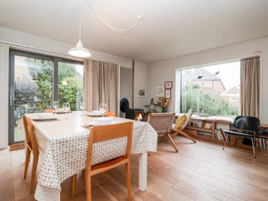 A dining room with a table set for four and a wood stove near large windows at Mundays in Orford