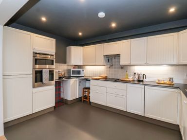 A kitchen with white cabinets black countertops and stainless steel appliances at Mundays in Orford