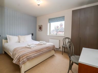 A bedroom with a bed with folded towels on it two chairs a wardrobe and a desk at Mundays in Orford