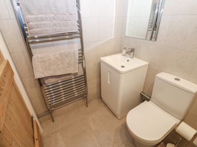 A bathroom with a toilet a sink with cabinet a mirror and a towel rack with towels at Swinhope View in Hexham