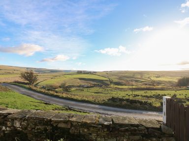A rural landscape with green fields a stone wall and a road at Swinhope View in Hexham