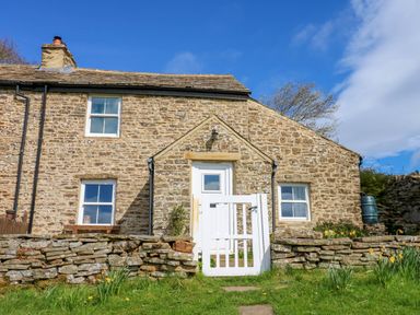 A stone house with a white wooden gate and grass in front at Swinhope View in Hexham
