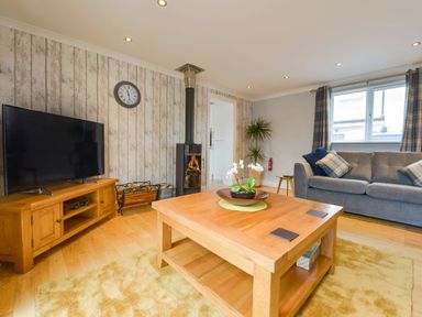 A living room with a wooden coffee table and a gray sofa near a window at Lilys Pad in Okehampton