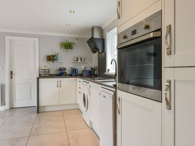 A kitchen with white cabinets built in oven washing machine dishwasher and countertop appliances at Lilys Pad in Okehampton
