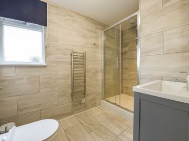 A bathroom with a toilet a heated towel rail a shower enclosure and a sink at Lilys Pad in Okehampton
