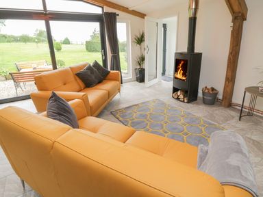 A living room with orange sofas a fireplace and large windows showing a garden at Windy Willows in Okehampton