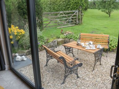 A patio with wooden benches and a table set with tea cups and a teapot at Windy Willows in Okehampton