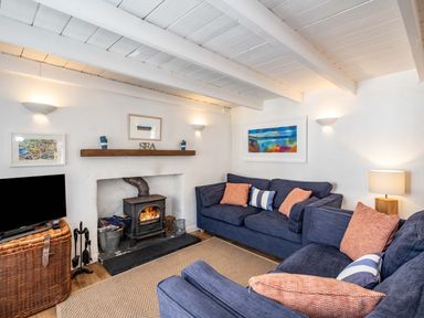 A living room with blue sofas and a wood burning stove at Sea Horses in Port Isaac