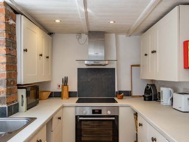 A kitchen with white cabinets a microwave a stove oven coffee machine kettle toaster and knife block at Sea Horses in Port Isaac