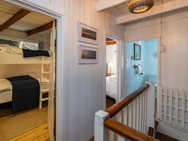 A hallway with doors leading to a bunk bed room a bedroom and a bathroom at Sea Horses in Port Isaac