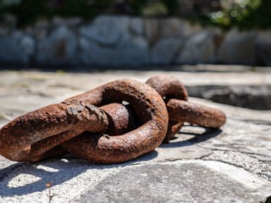 A close up of a rusty metal chain on a stone surface outdoors at Sea Horses in Port Isaac