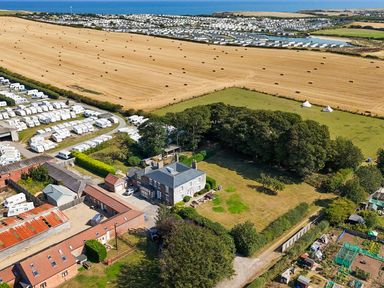 An outdoor view with caravans, a field, and a house at The Pheasantry in Flamborough