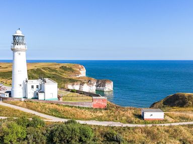 A lighthouse near the ocean with cliffs and a path at The Pheasantry in Flamborough