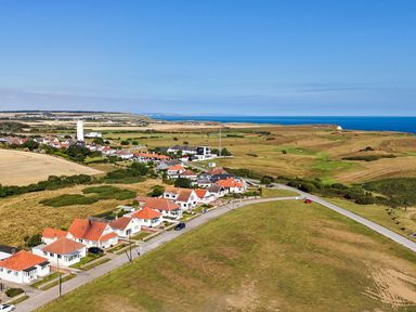 An aerial view of a coastal village with houses and a sea at The Pheasantry in Flamborough