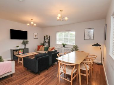 A living room with a television and dining table at The Pheasantry Flamborough