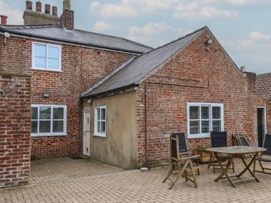 An outdoor area featuring a brick wall, windows, table, and chairs at The Pheasantry in Flamborough