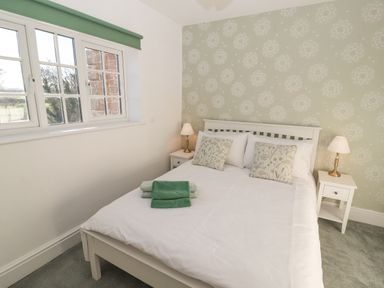 A bedroom with a white bed a pair of bedside tables with lamps and a window with green blinds at Hillside Hideaway in Wigton