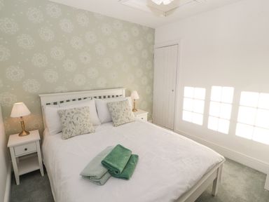 A bedroom with a white bed with pillows and folded towels and two bedside tables with lamps at Hillside Hideaway in Wigton