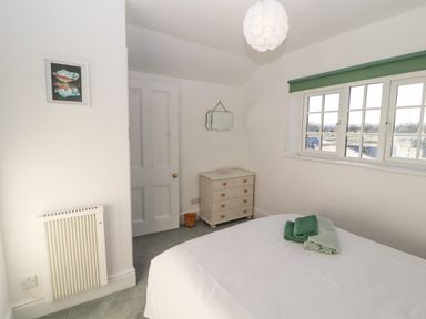 A bedroom with a bed and towels on it a chest of drawers a window and a door at Hillside Hideaway in Wigton