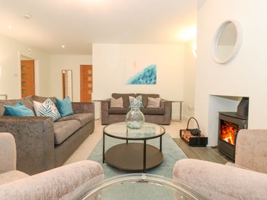 A living room with sofas a glass coffee table a fireplace and wooden doors at Tandarra in Keswick