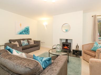 A living room with sofas a round glass coffee table a fireplace and a wall mirror at Tandarra in Keswick