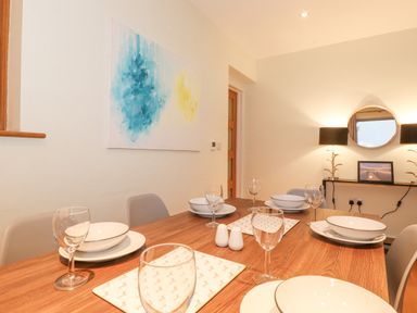 A dining room with a wooden table set with white bowls and wine glasses at Tandarra in Keswick