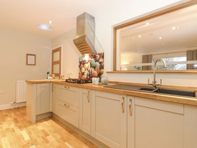 A kitchen with wooden counters a gas stove and a sink with a faucet at Tandarra in Keswick