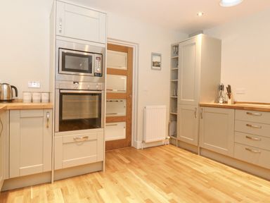A kitchen with built in microwave and oven wooden floor and cabinets at Tandarra in Keswick