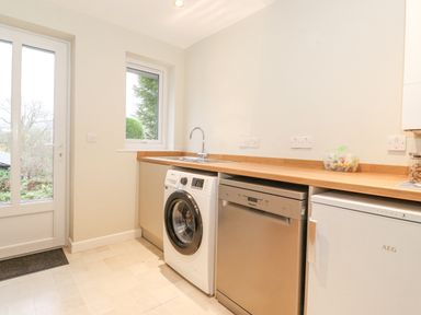 A utility room with washing machine dishwasher refrigerator sink and wooden countertop at Tandarra in Keswick