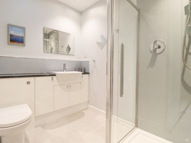 A bathroom with a toilet a sink under a mirror a shower enclosure and a framed picture on the wall at Tandarra in Keswick