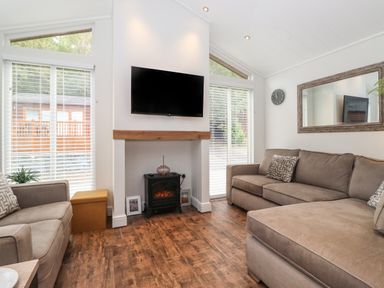 A living room with two sofas a wall-mounted tv and a small fireplace at Snuggledown Troutbeck 5 White Cross Bay near Windermere