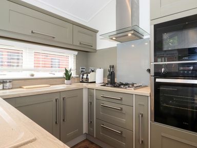 A kitchen with cabinets a gas stove an oven a microwave a toaster and a plant at Snuggledown in Troutbeck 5 White Cross Bay near Windermere