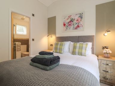 A bedroom with a bed stack of towels and an en suite bathroom at Snuggledown in Troutbeck 5 White Cross Bay near Windermere