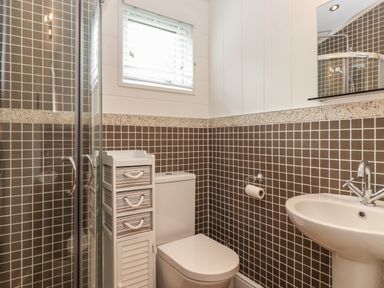 A bathroom with a toilet sink shower and storage cabinet at Snuggledown Troutbeck 5 White Cross Bay near Windermere