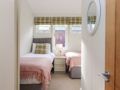 A small bedroom with two single beds a nightstand and a lamp at Snuggledown Troutbeck 5 White Cross Bay near Windermere