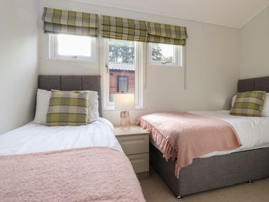 A bedroom with two single beds a bedside table and a lamp at Snuggledown in Troutbeck 5 White Cross Bay near Windermere
