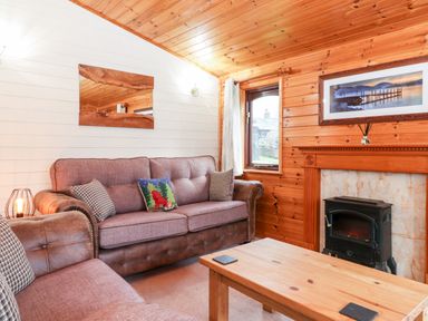 A sitting room with sofas a wooden coffee table a fireplace and a window at Latrigg Lodge Number 9 Burnside Park near Keswick