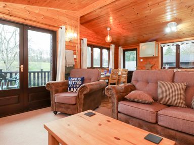 A living room with wooden walls and ceiling with sofas and a dining area at Latrigg Lodge Number 9 Burnside Park near Keswick