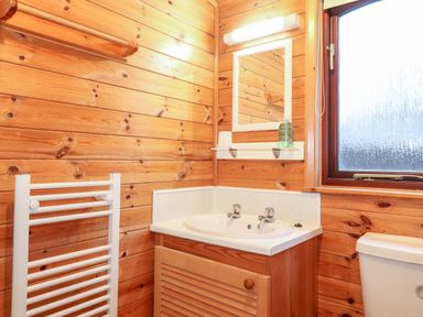 A bathroom with a sink, mirror, soap dispenser, towel rail, and a frosted window at Latrigg Lodge Number 9 Burnside Park near Keswick