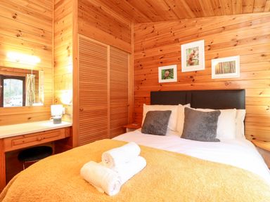 A bedroom with a bed with pillows and folded towels and a dressing table with a lamp at Latrigg Lodge Number 9 Burnside Park near Keswick