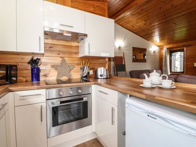 A kitchen with wooden countertops stainless steel oven toaster and white cabinets at Latrigg Lodge Number 9 Burnside Park near Keswick