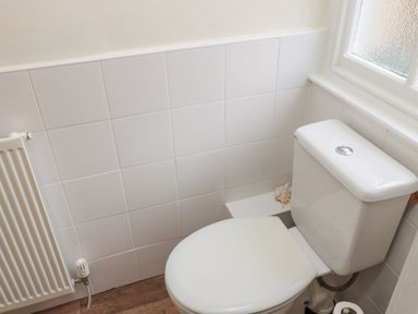 A bathroom corner with a white toilet next to a radiator and a frosted window at Courtyard Cottage in Alnwick