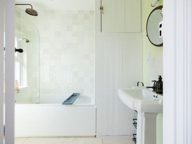 A bathroom with a bathtub shower and a sink with a round mirror at Tamarama House in Port Isaac