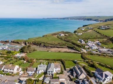 A coastal village with houses roads green fields and cliffs by the ocean at Tamarama House in Port Isaac