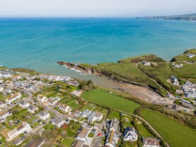 An aerial view of a coastal village with houses roads green fields and ocean cliffs at Tamarama House in Port Isaac